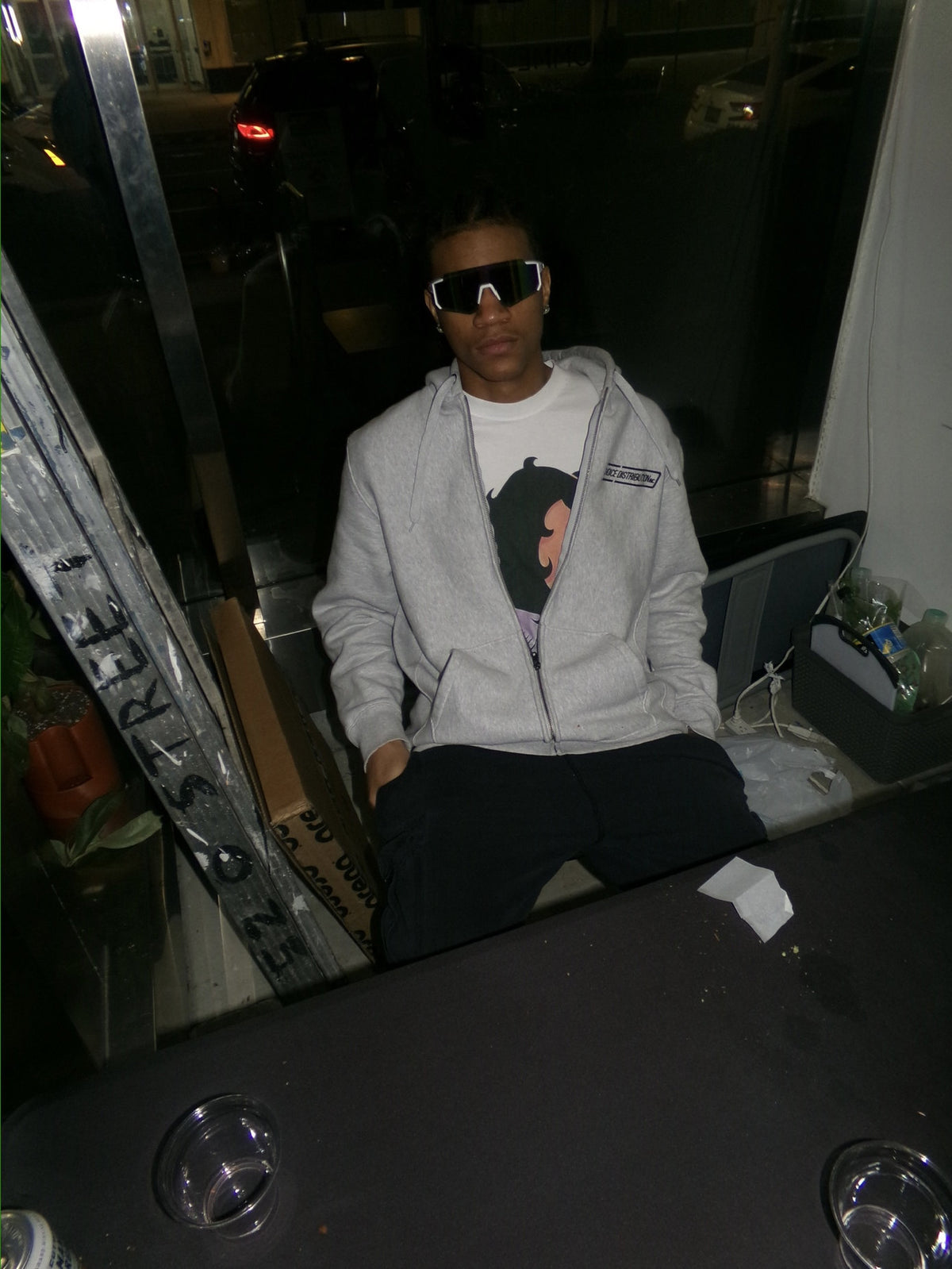 Streetwear editorial of a person wearing a gray hoodie by a storefront