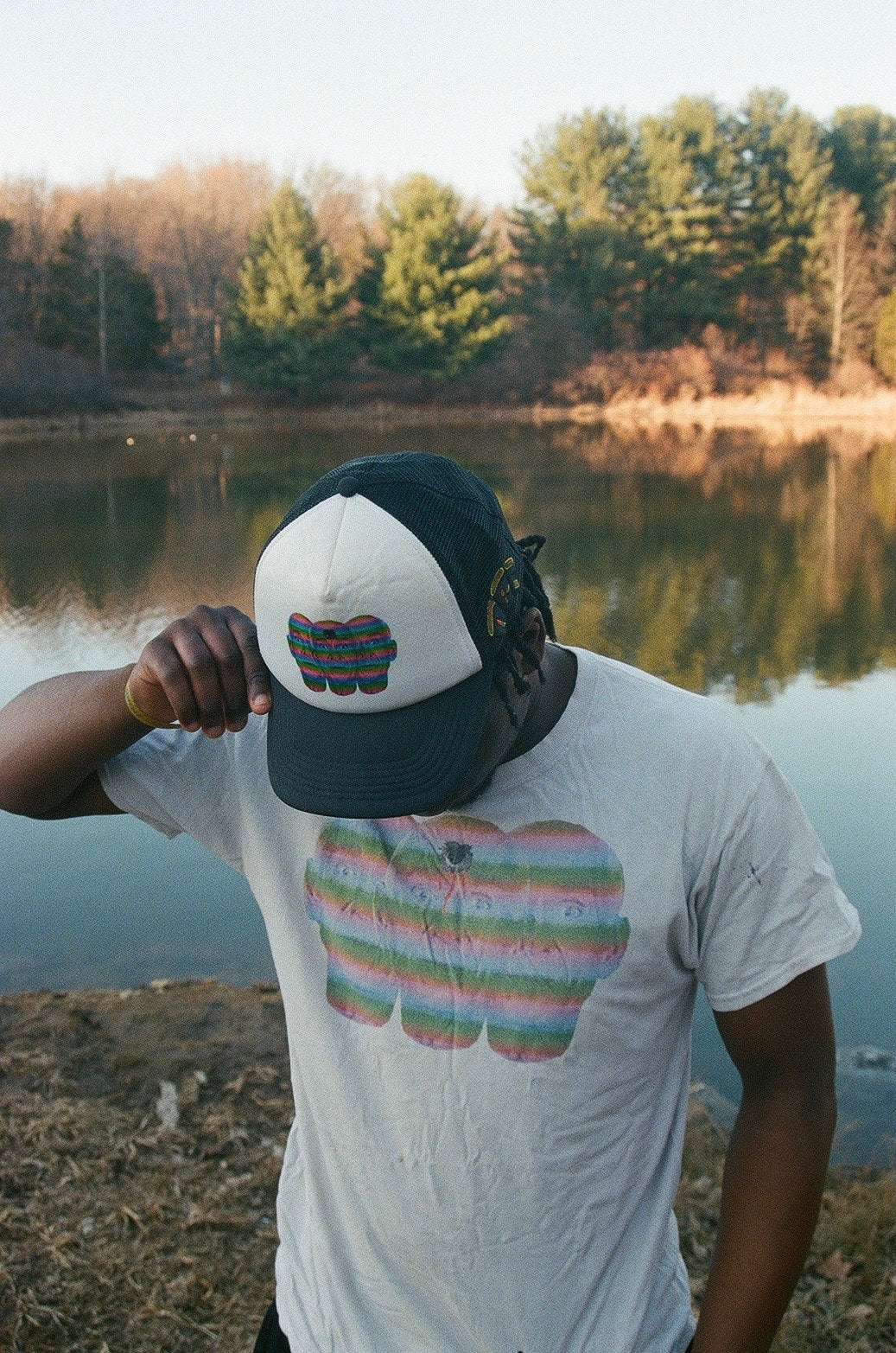 Person wearing a graphic white T-shirt beside a lake